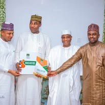 Four men in traditional dress and caps holding a presentation board bearing a map labelled Yabo/Shagari Federal Constituency.